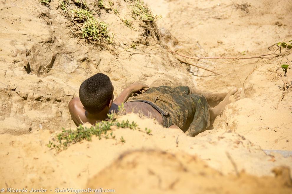 Imagem de um menino cheio de areia da Praia da Engenhoca.